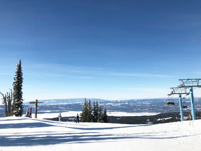 Ski lift at Brundage Mountain ski resort and panoramic views of snow-covered mountains.
