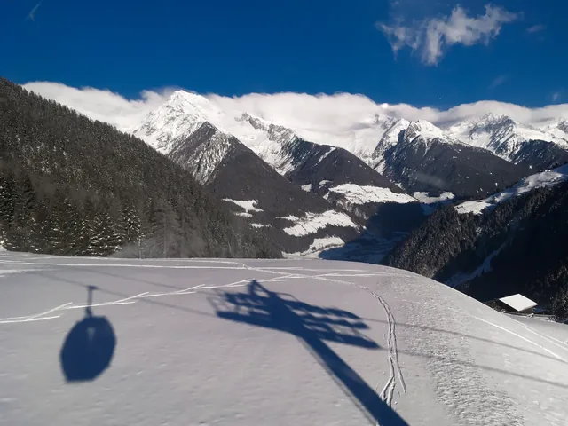 Cable car lift shadow silhouette on fresh snow with Aurina valley and mountains in Speikboden ski resort in Italy