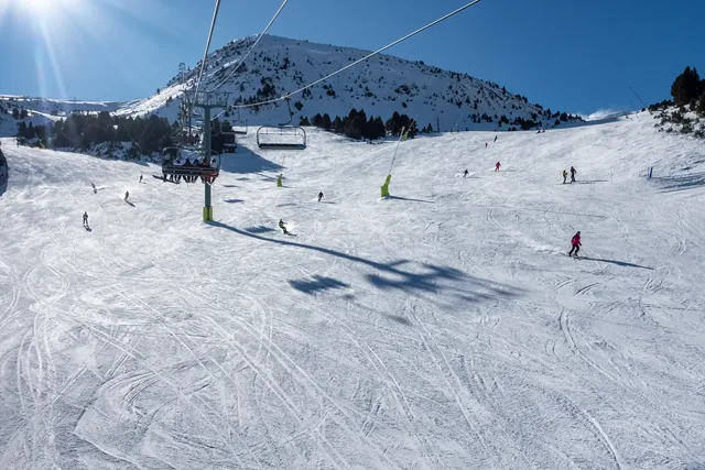 Ski slope with skiers sliding down the slope in the Pyrenees, Andorra, photo with copyspace.