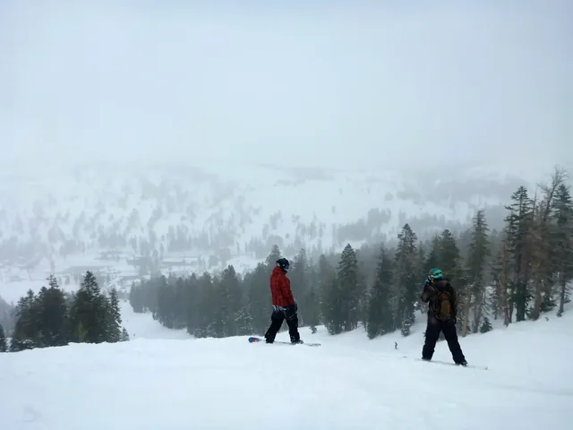 Landscape view of skiers and snowboarders on the slopes of a ski resort on a foggy day