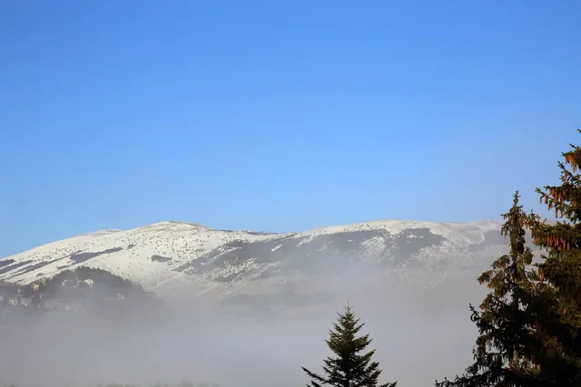 Snow-capped mountain range suspended between blue sky and soft fog, Pescocostanzo, Abruzzo, Italy
