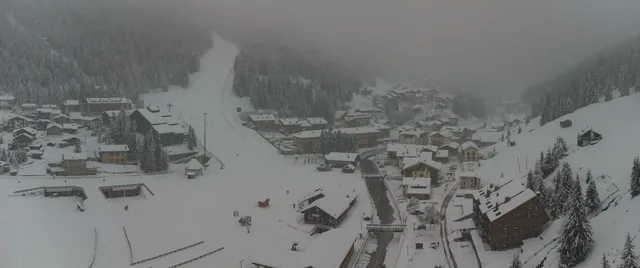 Aerial drone panorama of Santa Caterina di Valfurva village during a heavy snow storm in winter. Visible ski slope
