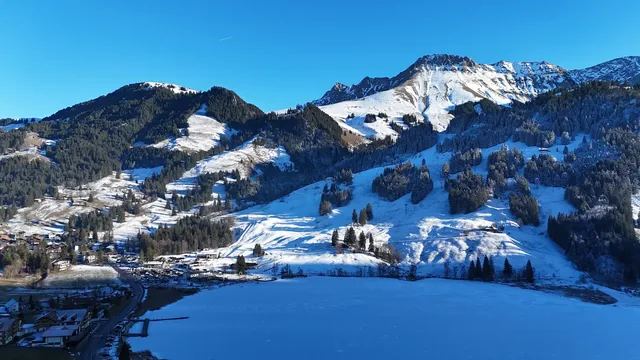Frozen Schwarzsee lake and ski resort surrounded by snowy mountains in the Swiss Prealps