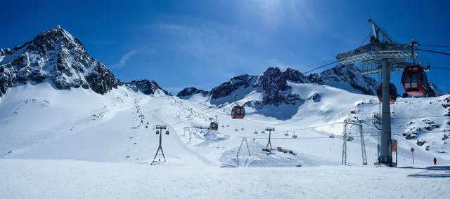 Stubai glacier in Austrian Alps with ski slopes, cable car gondolas, chairlift with skiers and snowboarders